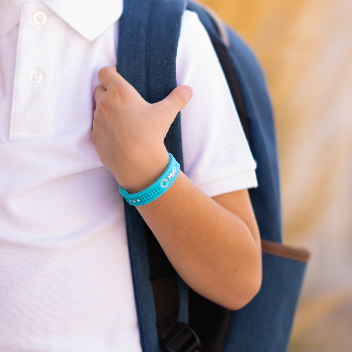 Child with a backpack wearing a teal MyID medical ID bracelet